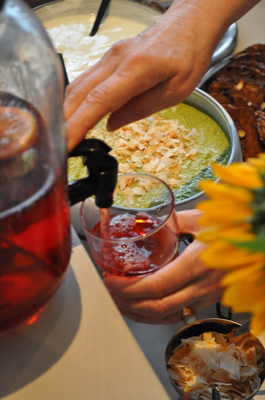 Een drankje wordt ingeschonken naast granola en kokos bij OAAS
