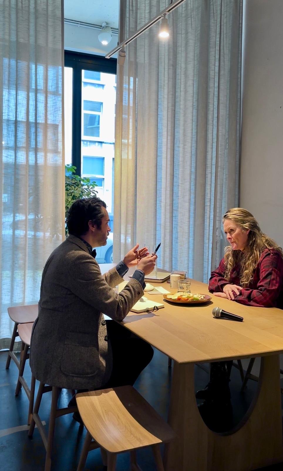 Twee mensen aan de houten tafel in de meetingroom van OAAS