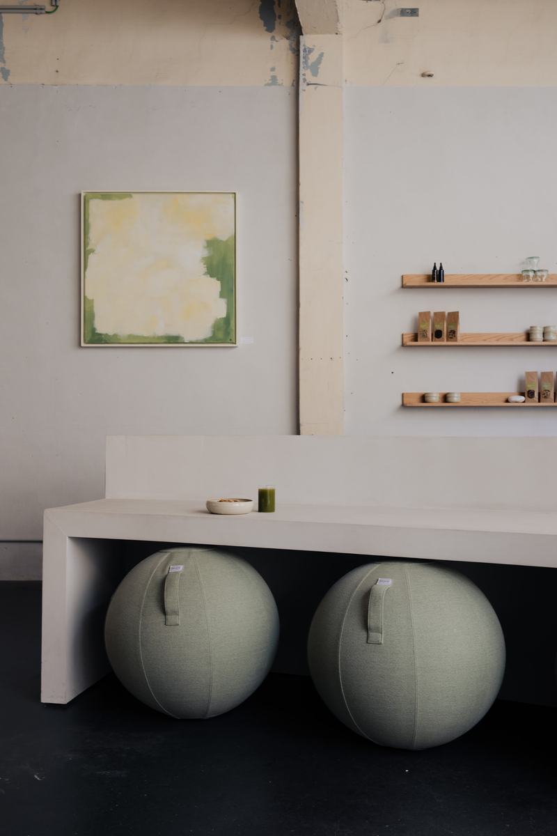 Witte bar met groene zitballen, een schilderij en wandrekken